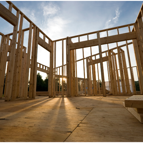 The sun is shining through the wooden frames of a house under construction