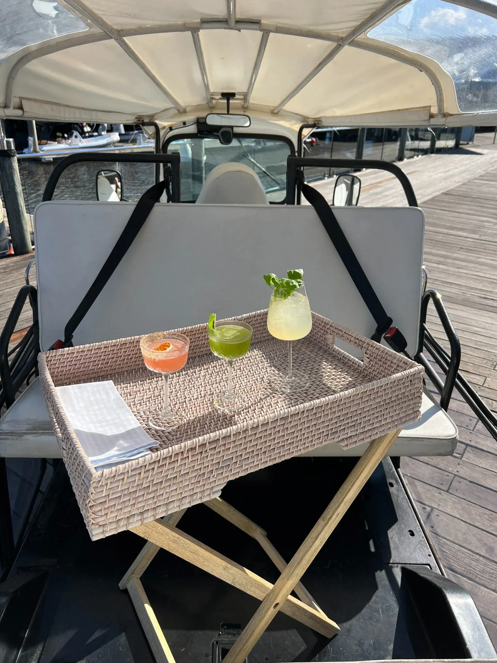 Cocktails on a woven tray in a Tuk Tuk tour. Wooden stand on a pier.