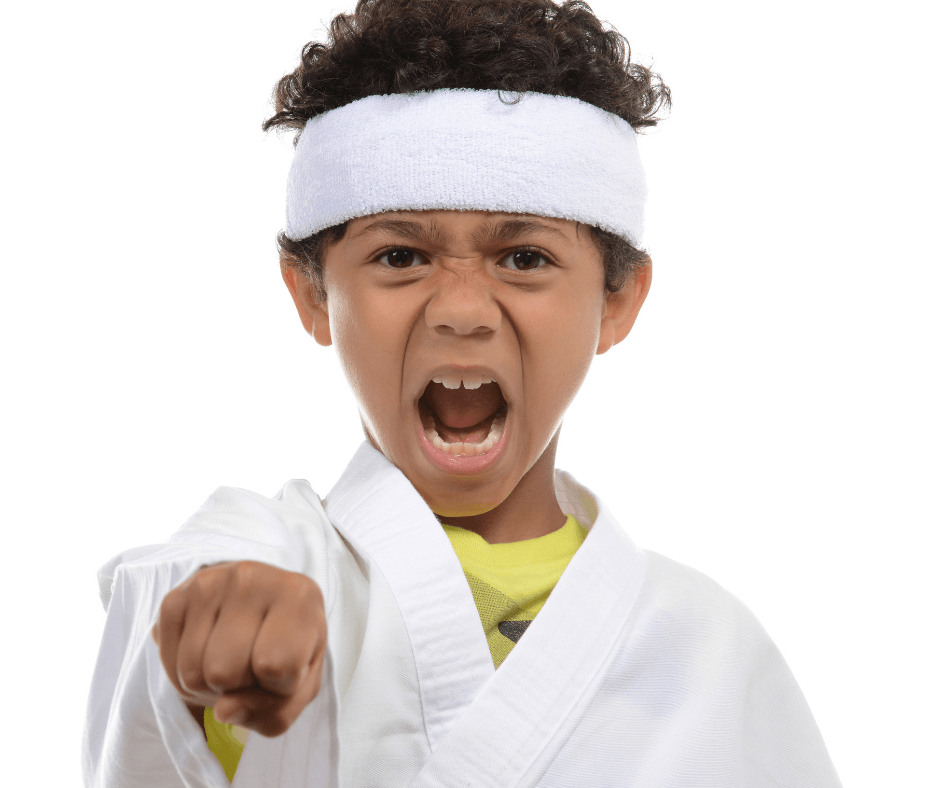 A young boy in a karate uniform is pointing at the camera.