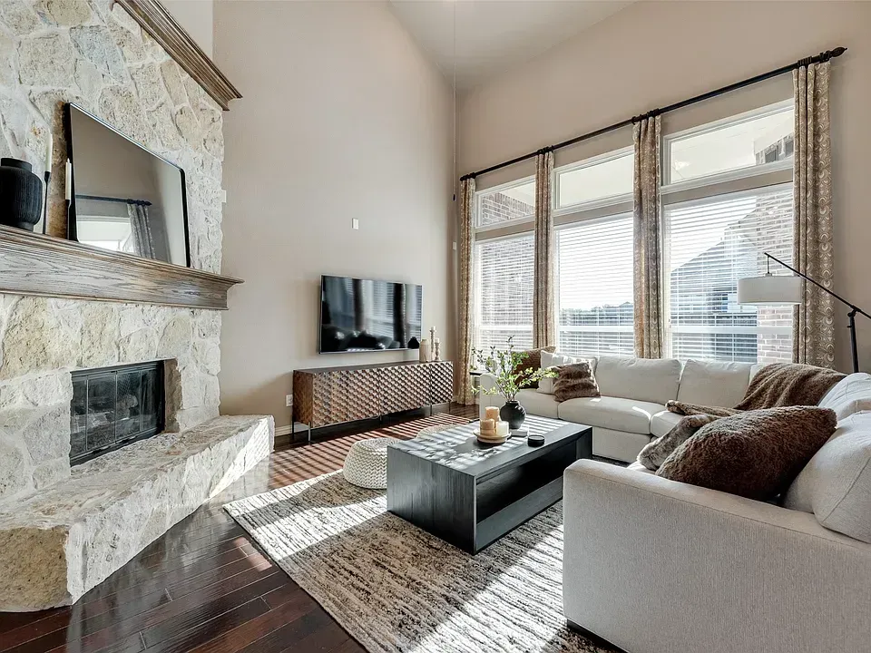 Modern living room with stone fireplace, large windows, and neutral sectional sofa