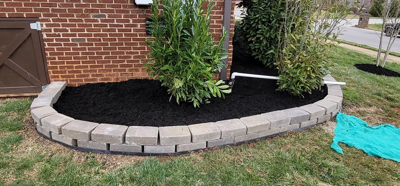 A brick wall with a planter in front of a brick house