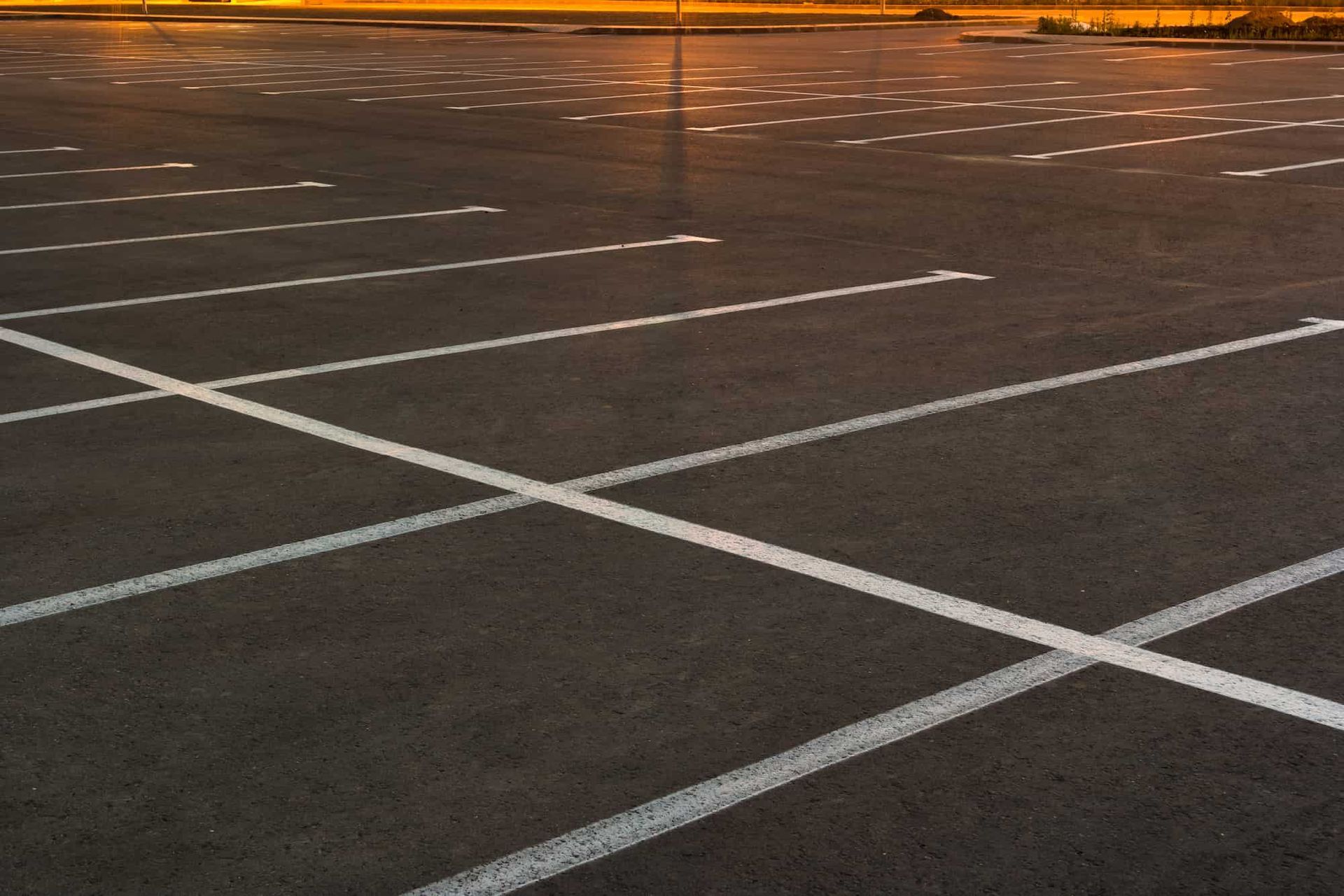 Empty asphalt parking lot with white painted lines.