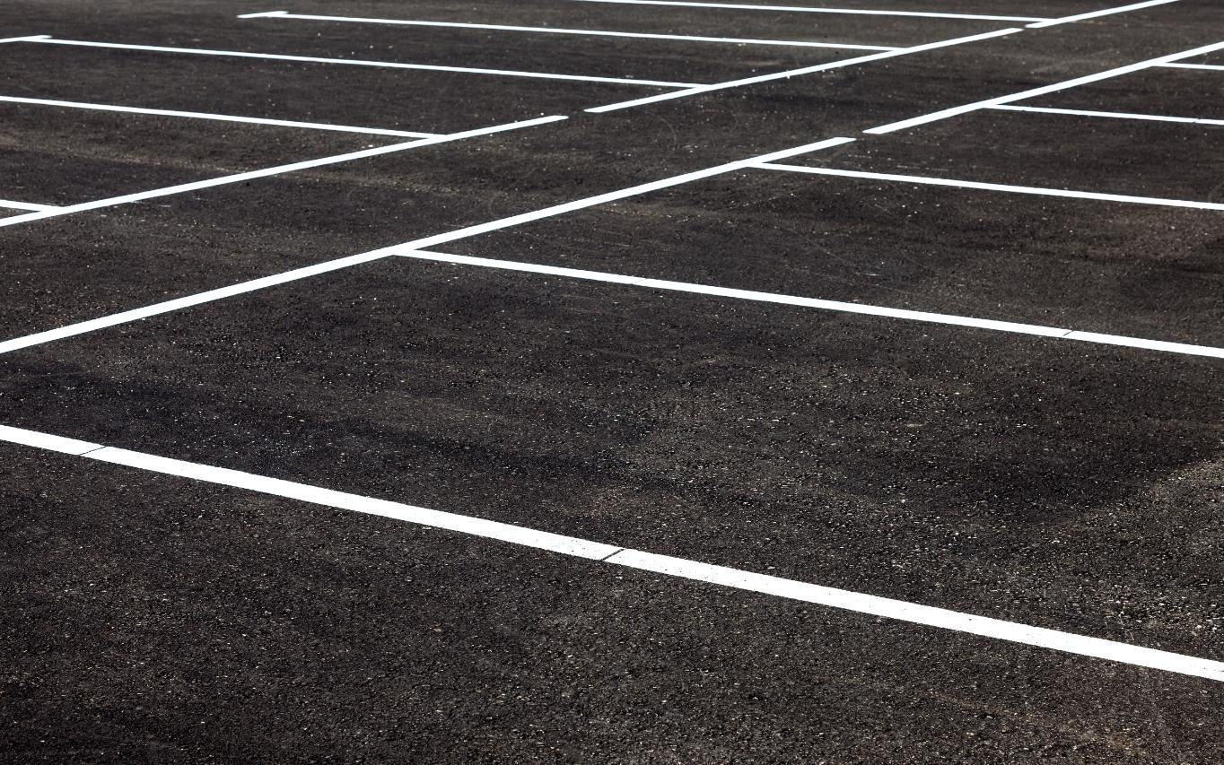 Asphalt parking lot with white painted parking space lines.