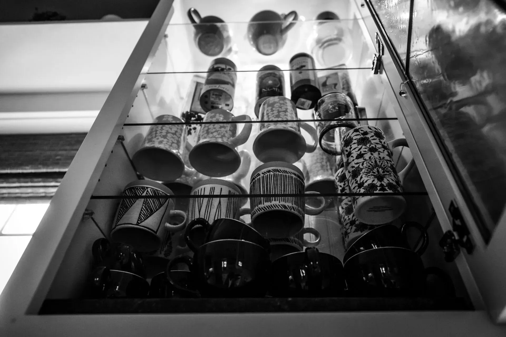 A black and white photo of a drawer filled with coffee mugs