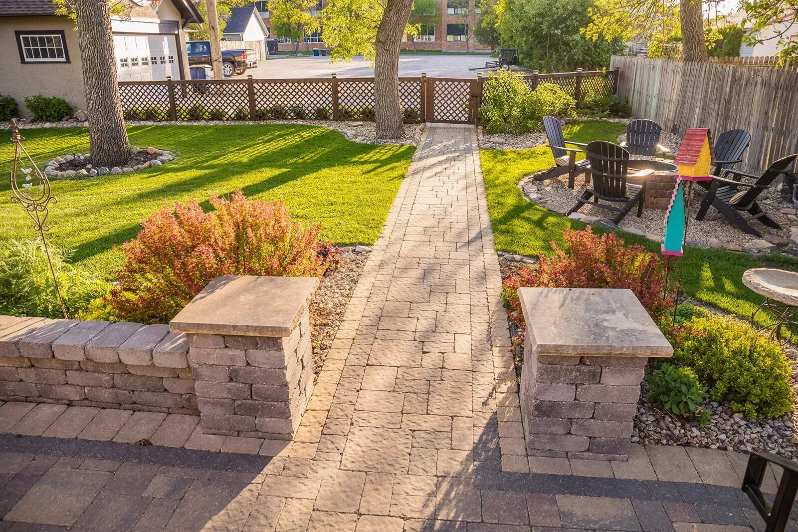 A brick walkway leading to a patio with chairs and umbrellas.