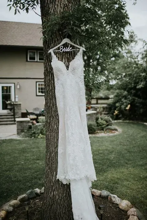 A wedding dress is hanging from a tree