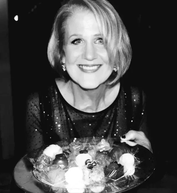 A woman is smiling while holding a plate of food