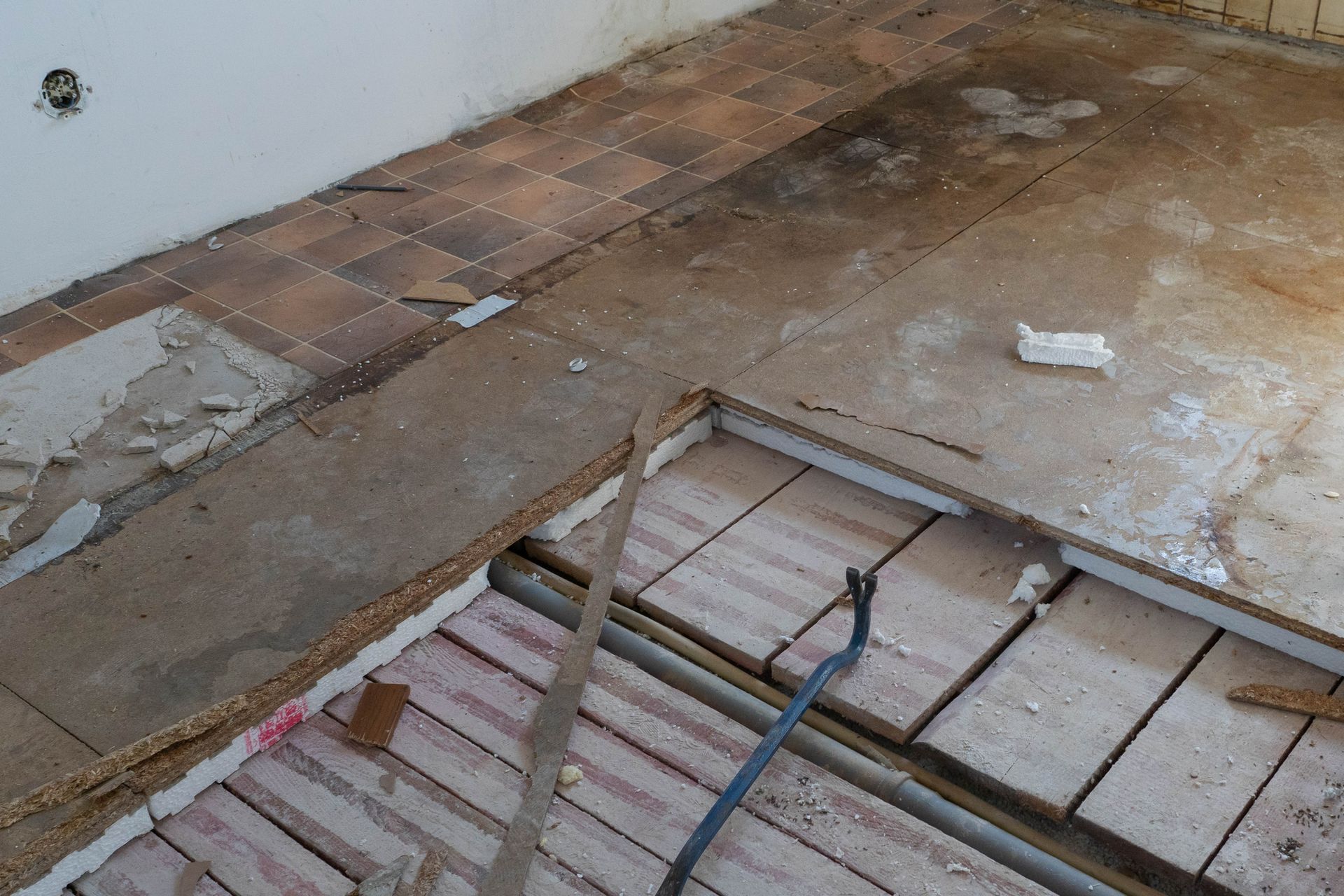 Suelo parcialmente demolido, con viguetas, tablones y escombros a la vista en una habitación en obras