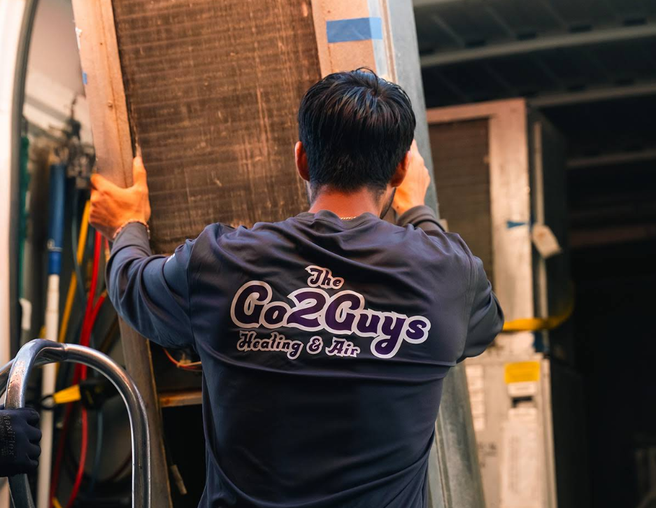 Worker in dark shirt carrying a large panel at a workshop entrance