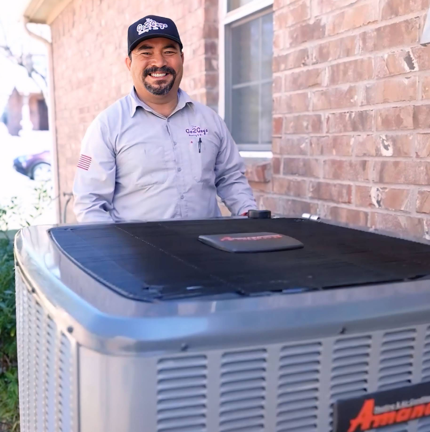 Man smiling beside a large outdoor HVAC unit next to a brick wall