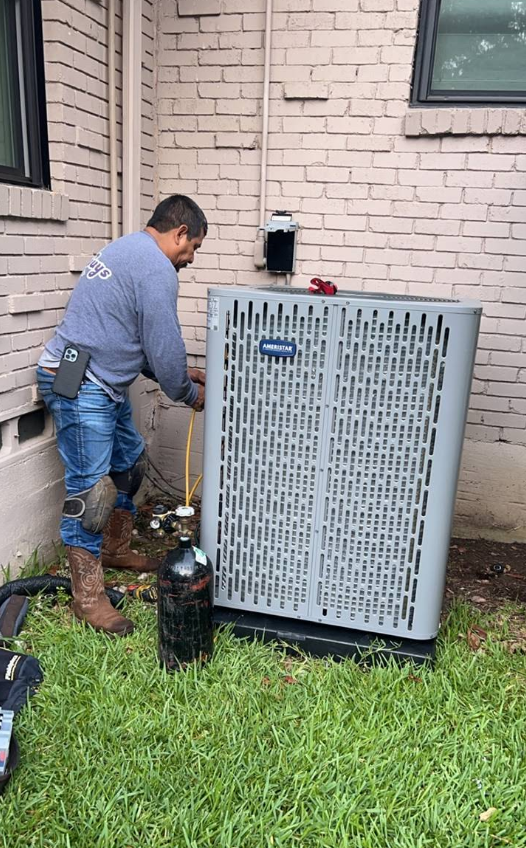Technician inspecting outdoor HVAC unit beside a house, with tools on the grass.