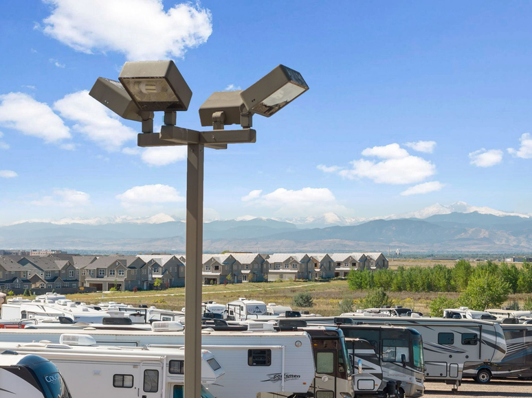 RV storage lot with mountain backdrop, clear sky, and a tall light post.