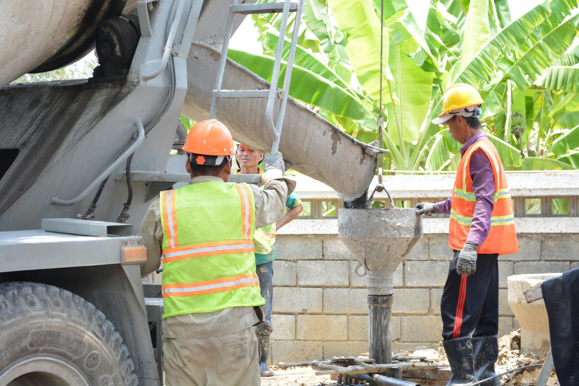 Construction workers in hard hats pouring concrete from a mixer truck into a form
