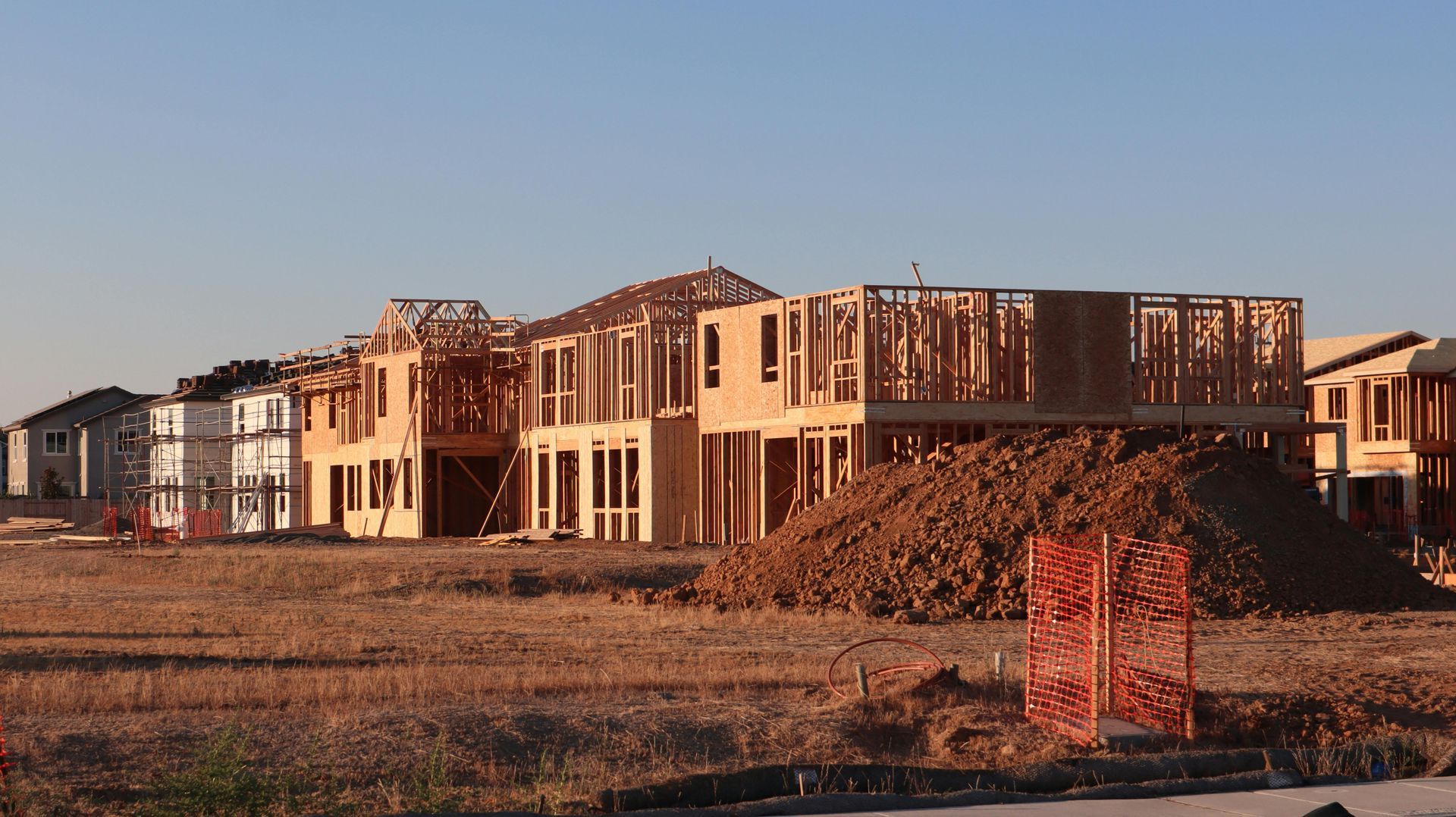 Partially built suburban homes at a construction site in warm sunlight