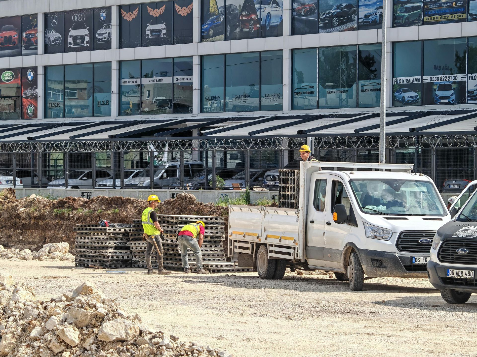 Construction site with concrete excavation and a yellow crane lifting debris beside retaining walls