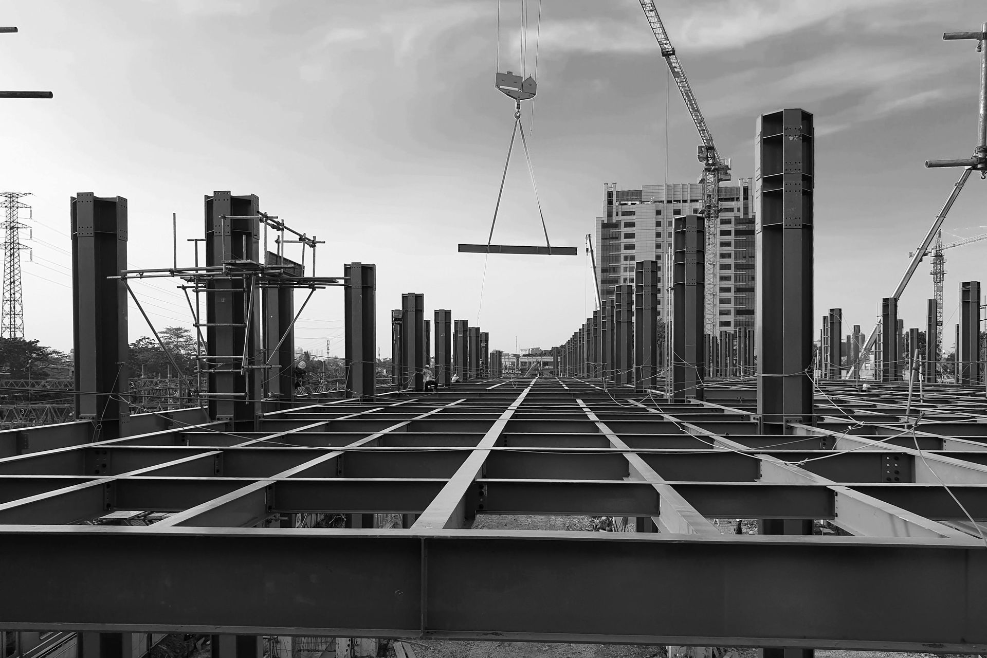 Construction site with steel framework, cranes, and high-rise buildings in the background