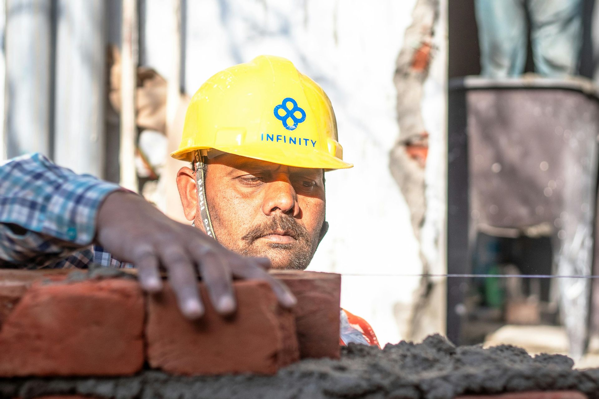 Construction worker in yellow hard hat stacking bricks at a job site