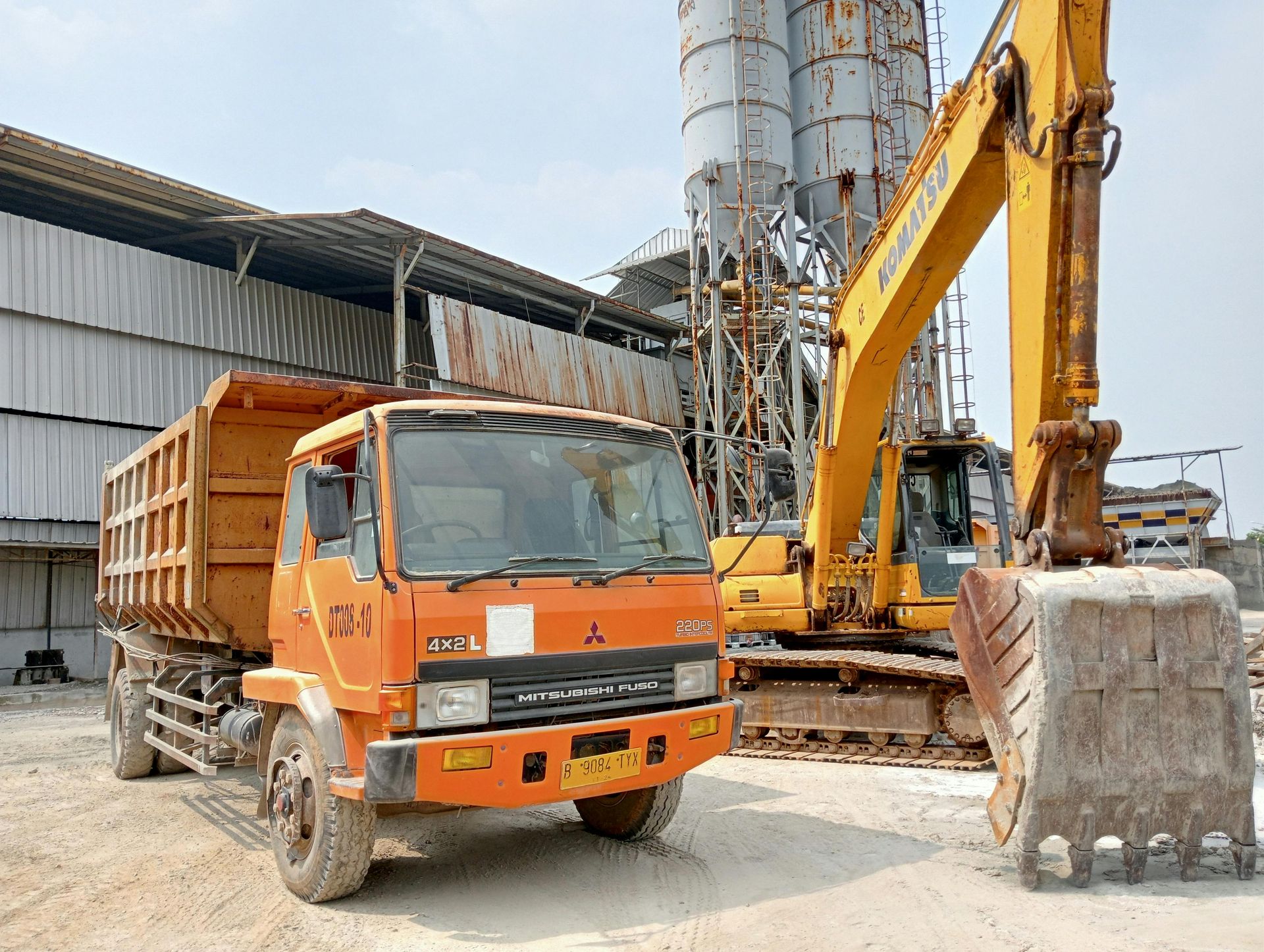 Yellow crane loaded on flatbed truck at a construction site, with workers nearby.