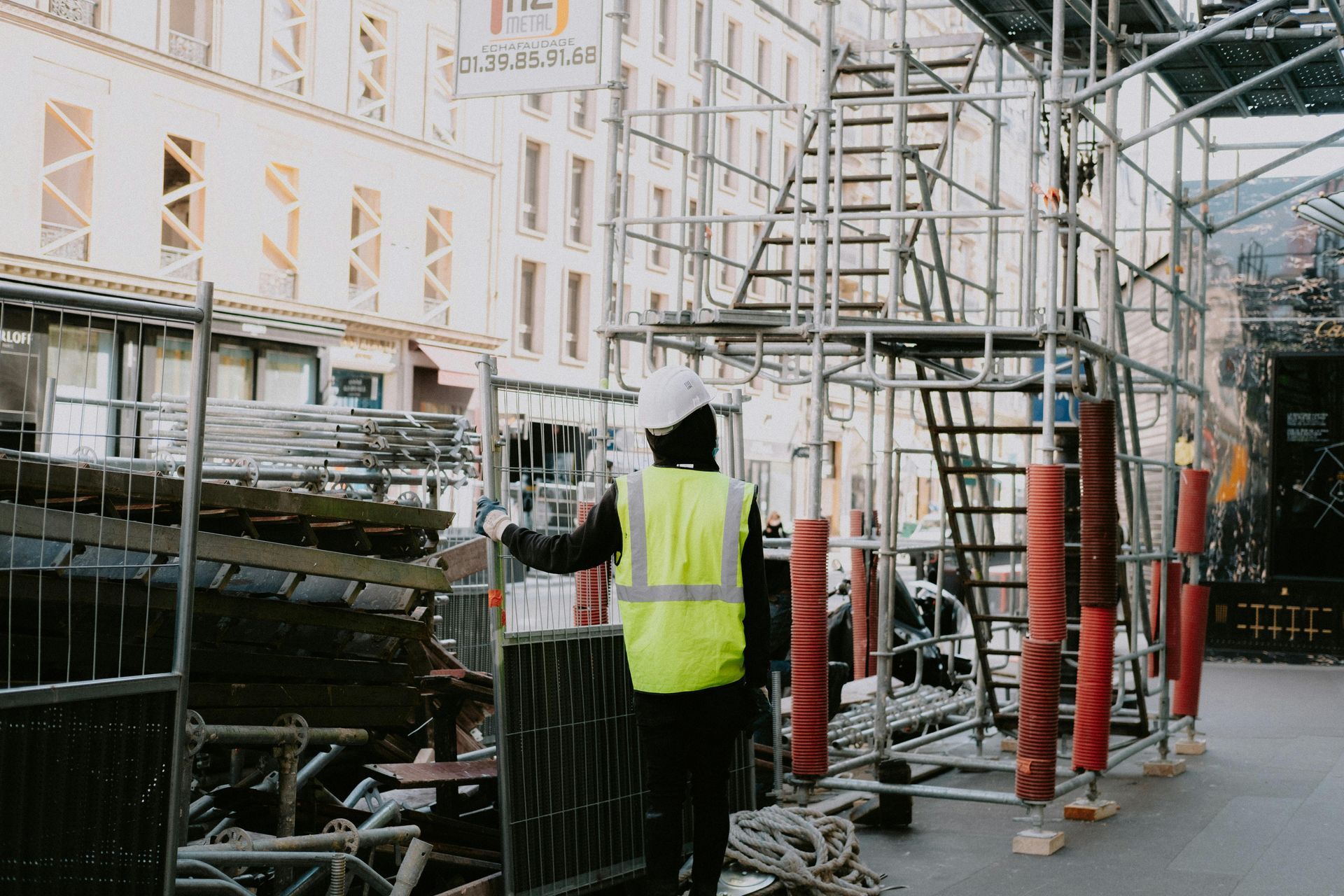Construction worker in yellow vest standing by scaffolding on a city street