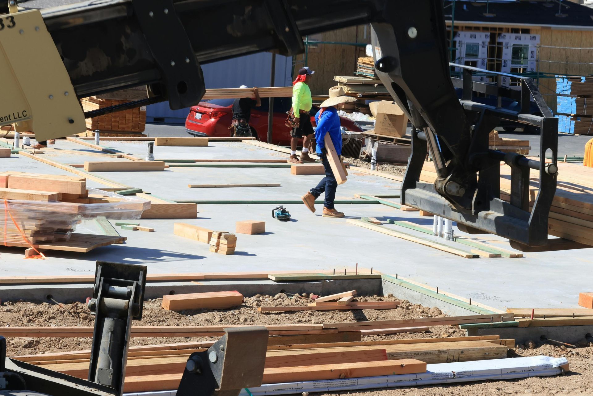 Construction workers guiding a large raised structure over a wooden deck foundation.