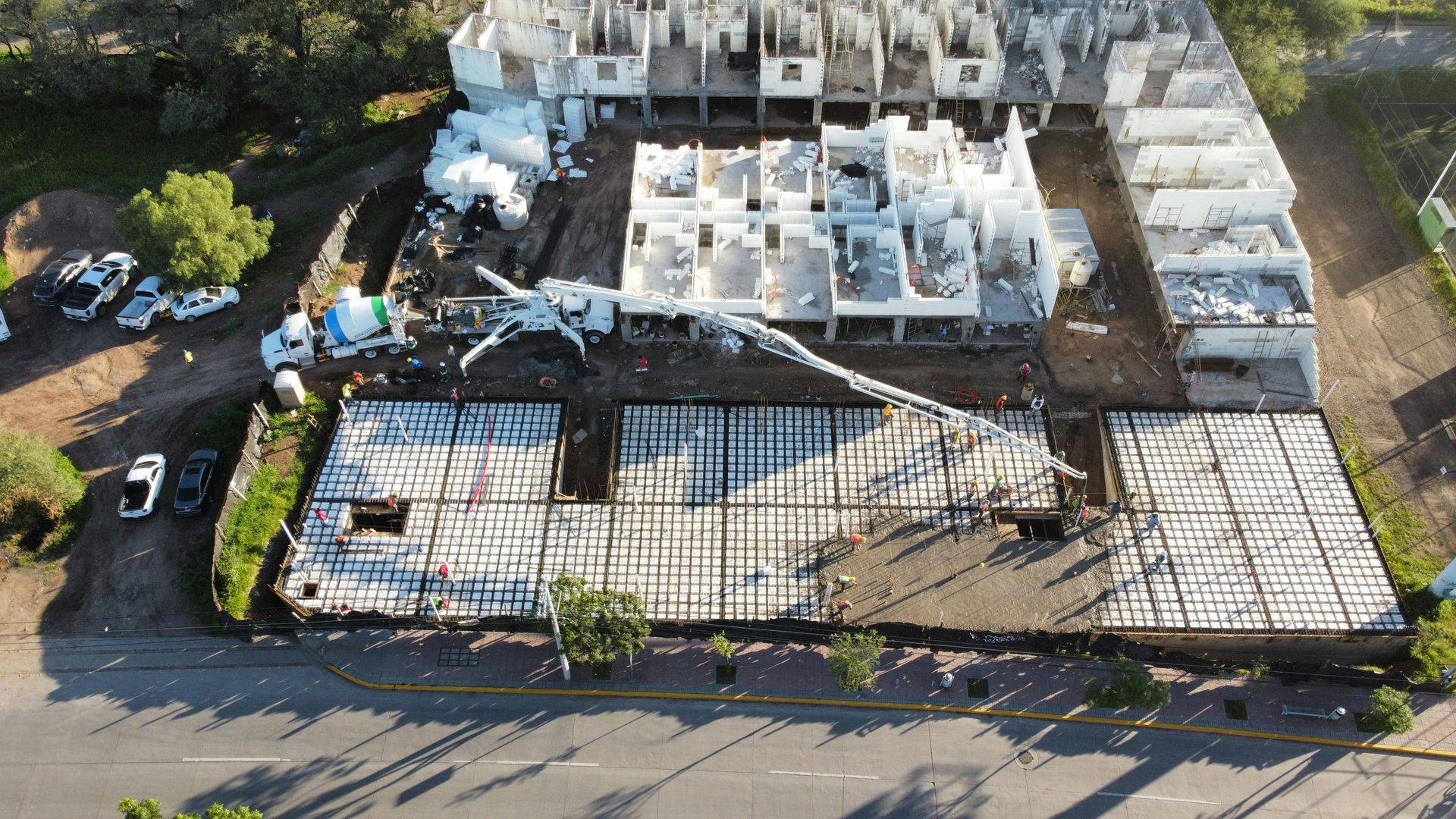 Aerial view of a damaged building under construction with debris, exposed concrete, and a street in front.