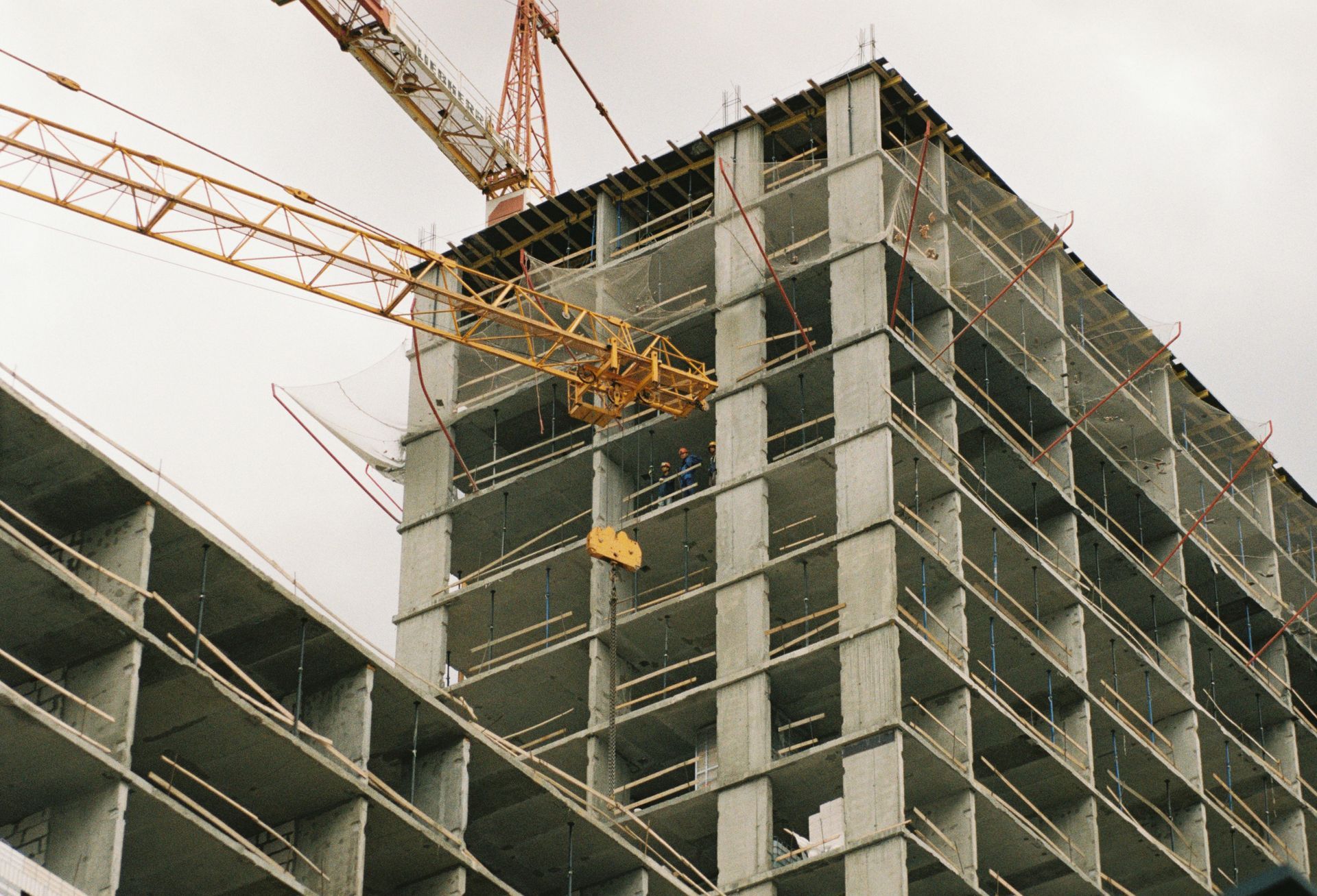 High-rise building under construction with a crane against a cloudy sky