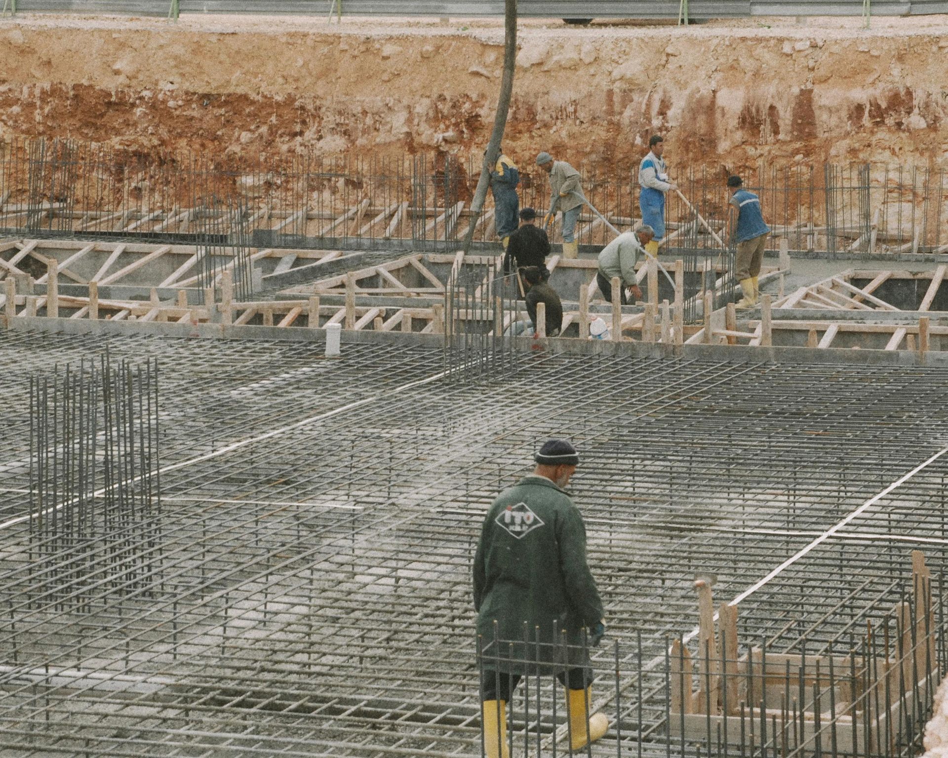 Construction site with workers over a rebar foundation in a concrete pit