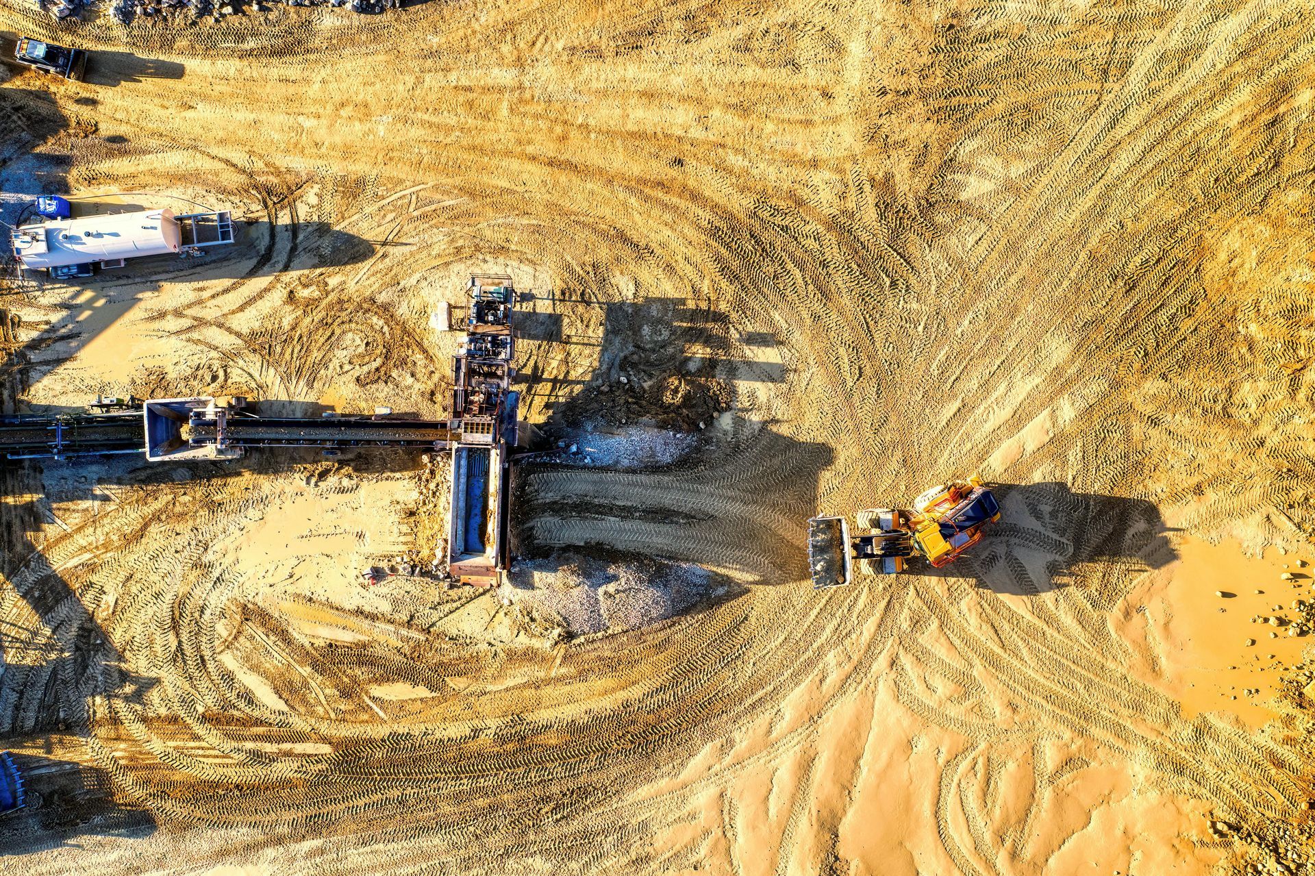Aerial view of a construction site with heavy machinery digging in a large sandy excavation area.