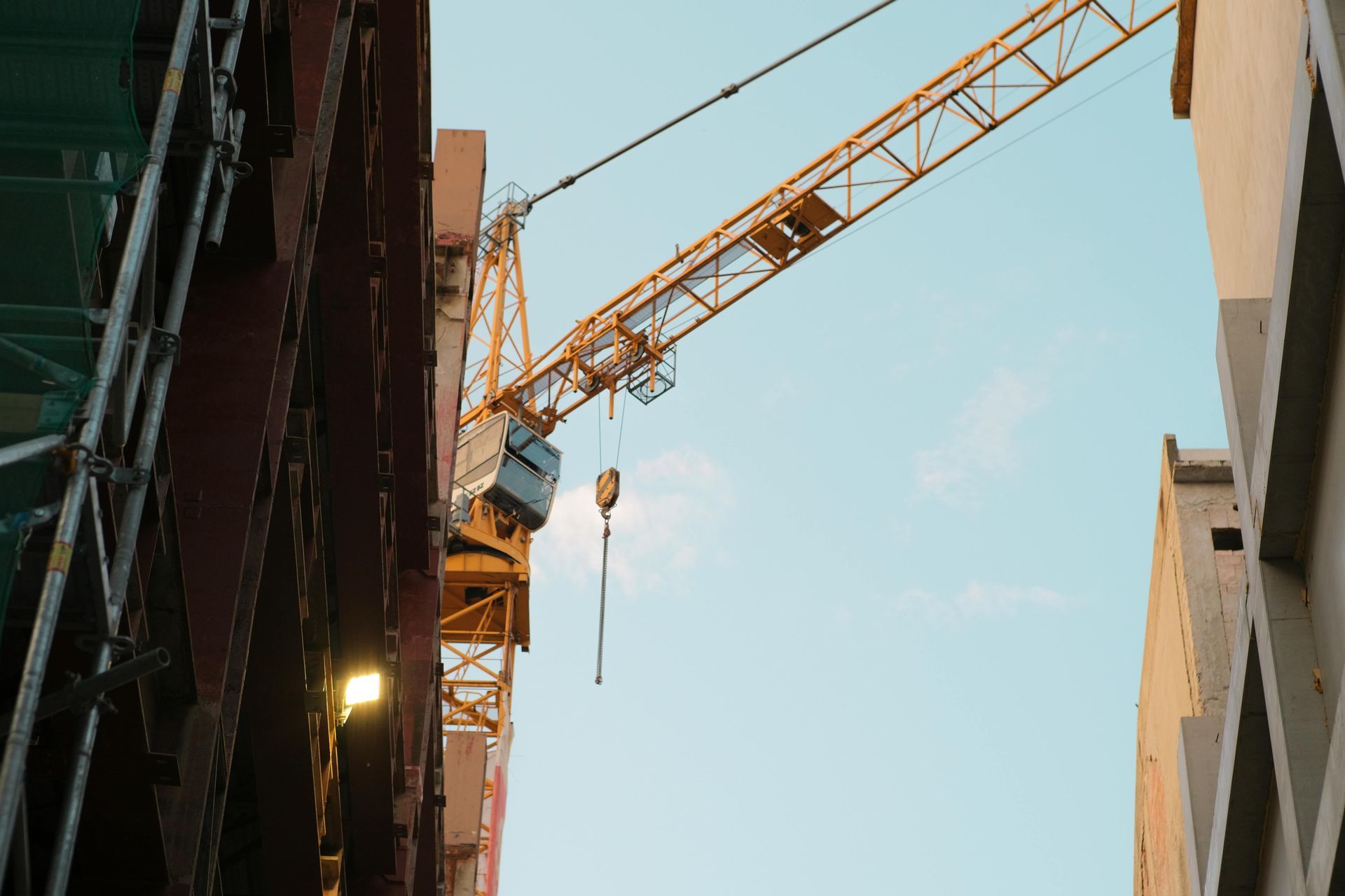 Construction crane between tall buildings against a blue sky