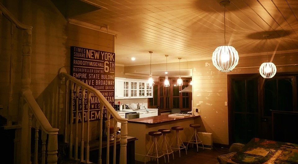 Interior with a staircase, kitchen, and bar. Warm lighting from pendant lights. Brown, white and tan color scheme.