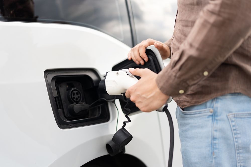 Person plugging a charging cable into an electric car.