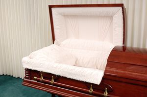Open casket with white satin lining and a wooden exterior in a funeral setting