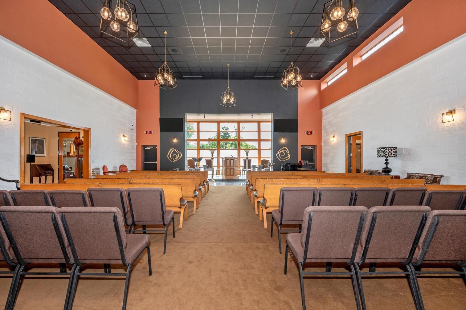 Church sanctuary with rows of pews, a central aisle, and a cross-shaped window at the front