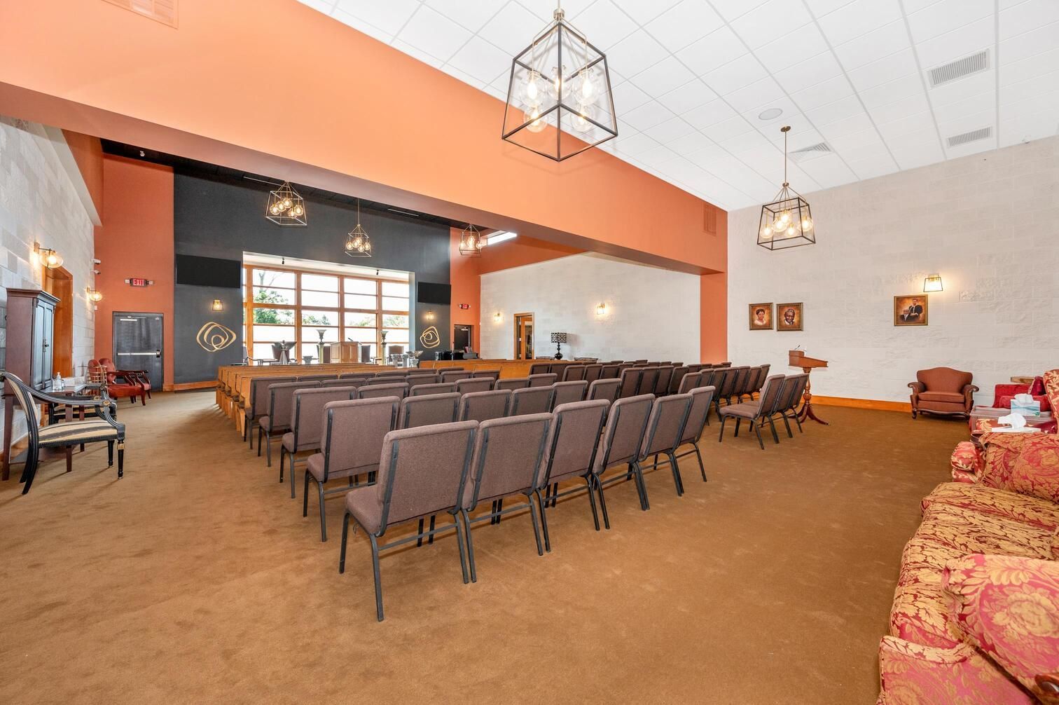Large conference room with rows of chairs, orange walls, and chandeliers