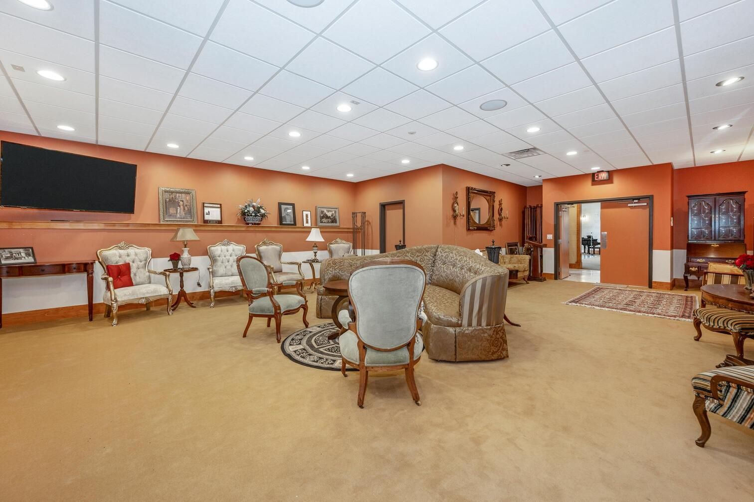 Spacious orange lounge with sofas, chairs, tables, and a fireplace under a white ceiling
