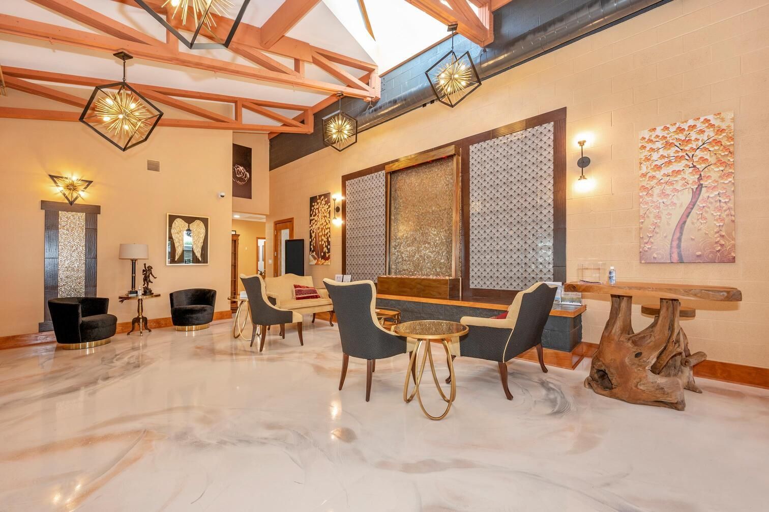 Spacious modern living room with marble floor, wood beams, chandeliers, and a round table with dark chairs.