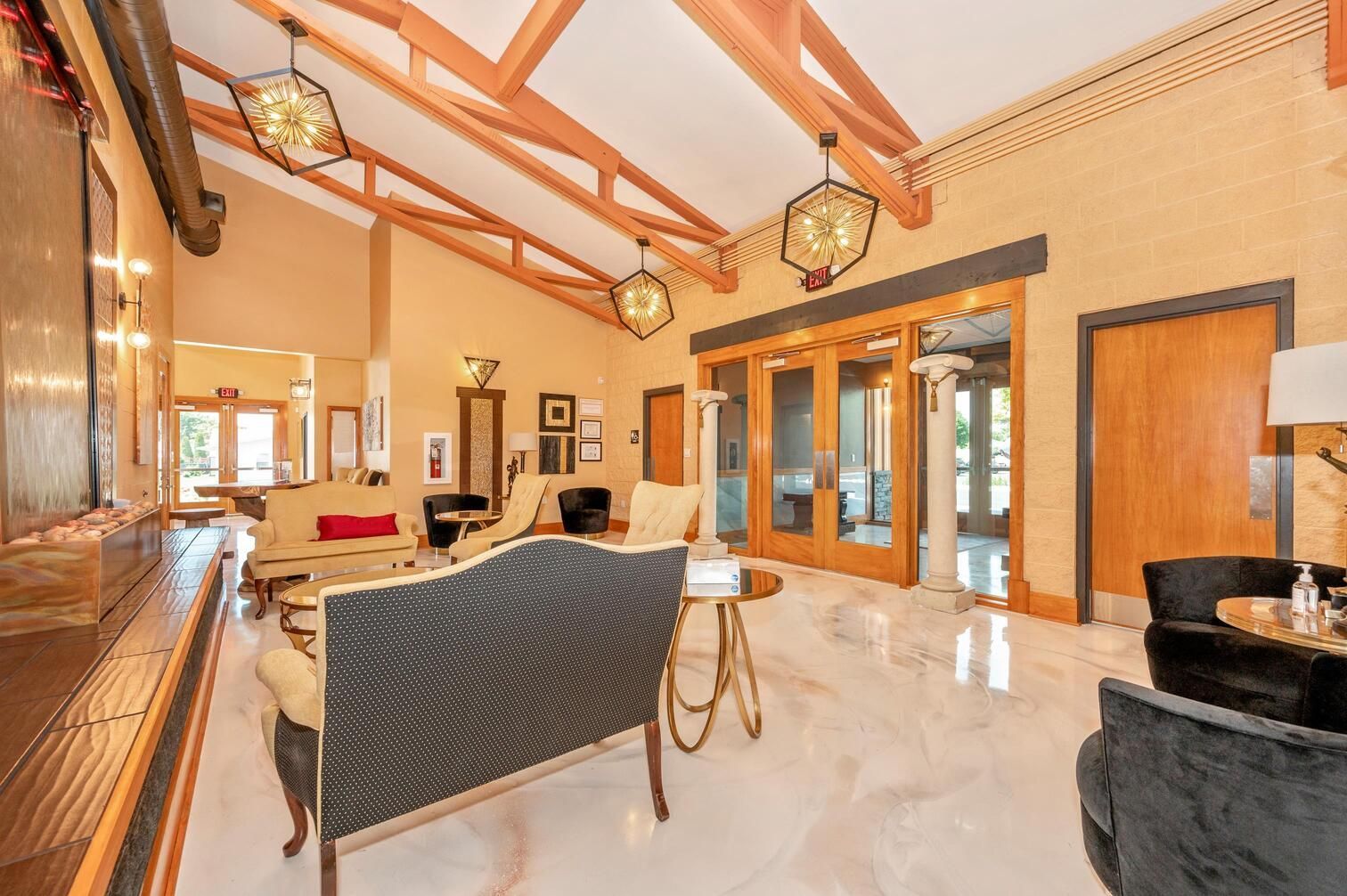 Spacious living room with high wood beams, marble floor, and leather seating near large glass doors