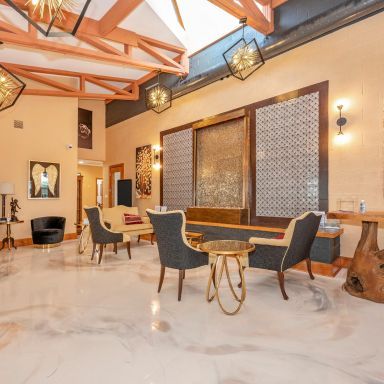 Elegant lobby with lounge seating, marble floor, high wood-beamed ceiling, and warm pendant lights