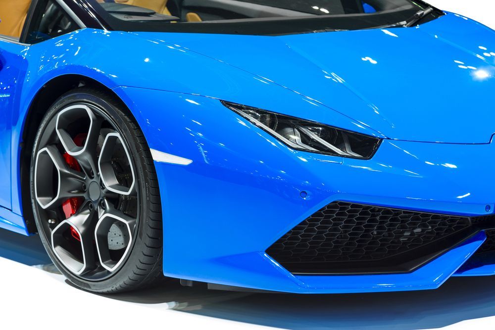A blue sports car is parked on a white surface.