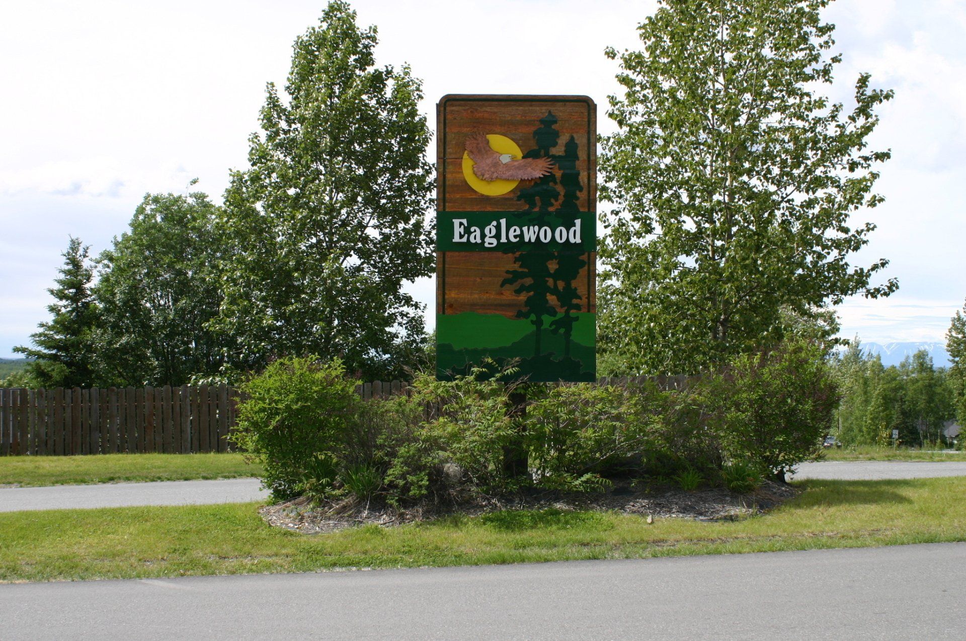 Sign for Eaglewood with trees and a crescent moon.