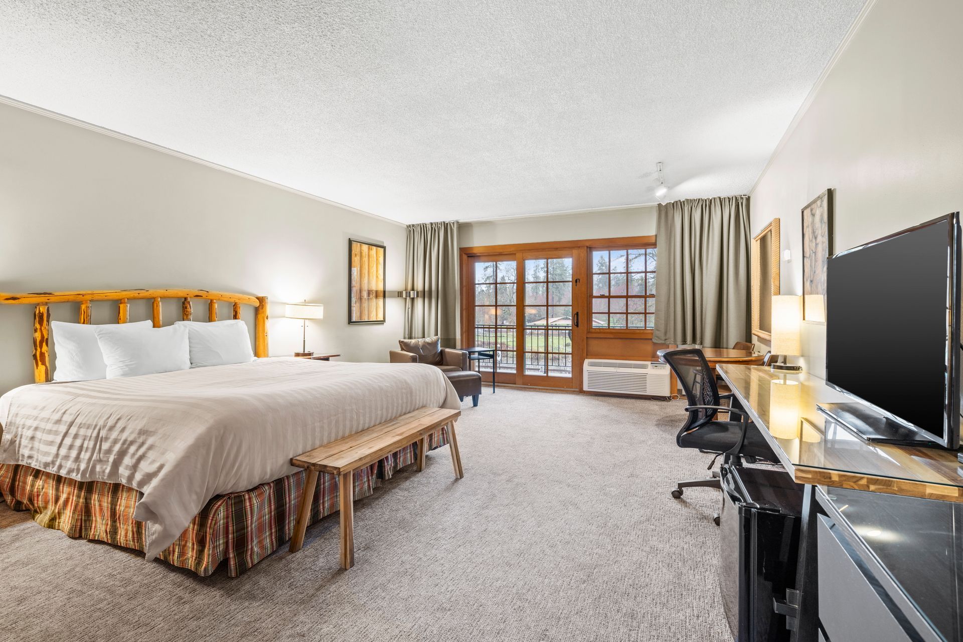 Hotel room with king bed, TV, desk, and balcony doors