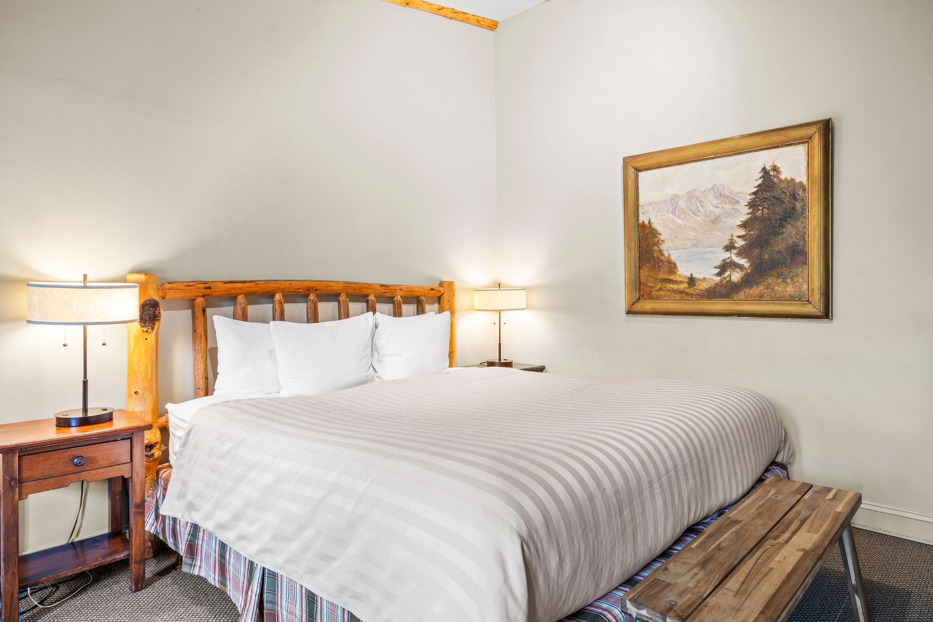 Bright hotel bedroom with a large bed, bedside lamps, and framed wall art