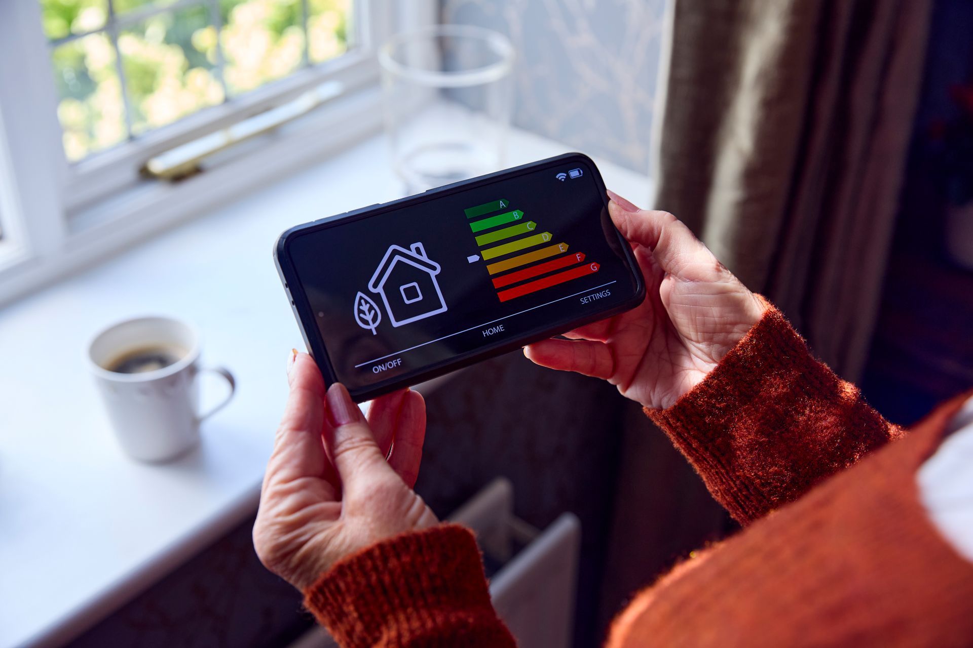 Persona che tiene in mano un telefono e mostra un grafico dell'efficienza energetica