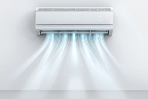 White air conditioner unit blowing cool air onto a white wall.