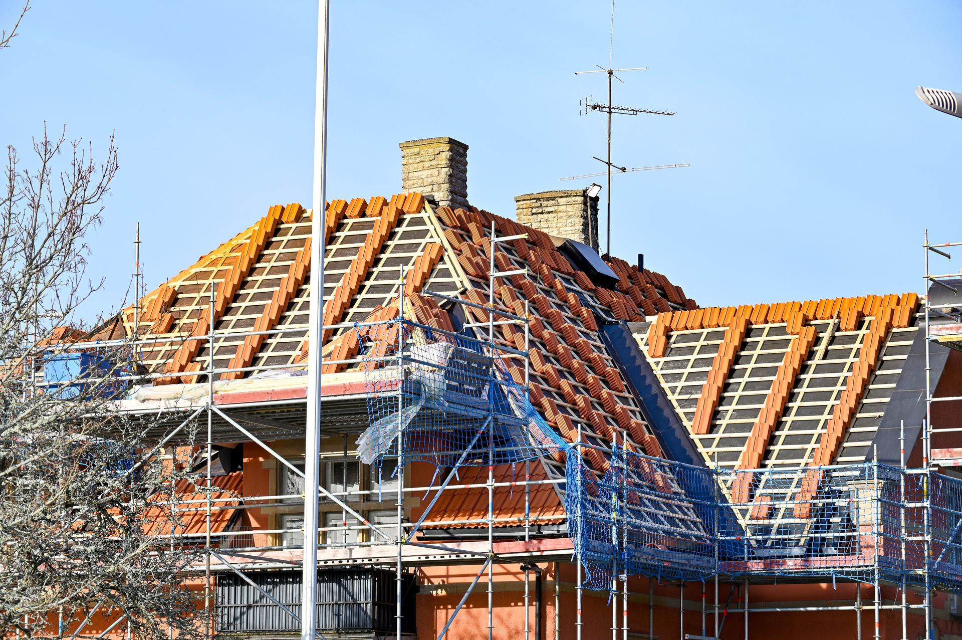 Toiture de maison en construction avec des tuiles orange et des échafaudages.