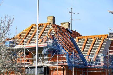 Toiture de maison en construction avec des tuiles orange et des échafaudages.