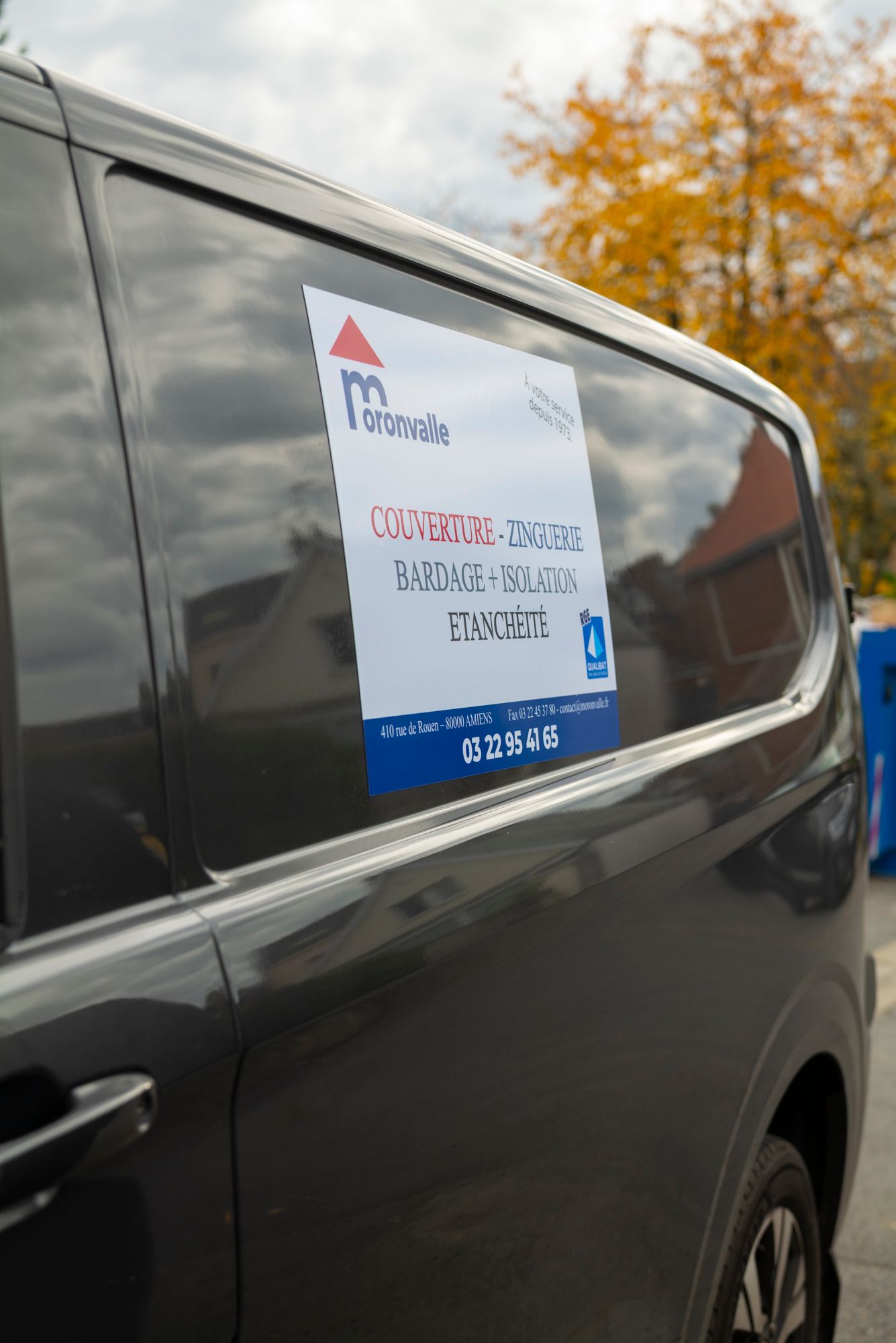 Camionnette grise avec publicité sur le côté, garée à l'extérieur.