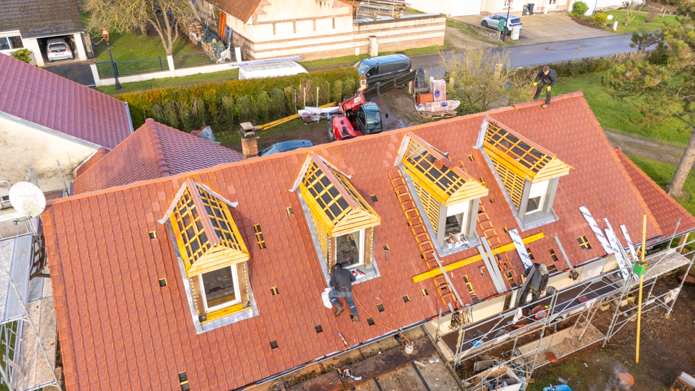 Maison en construction avec plans et schémas enroulés.