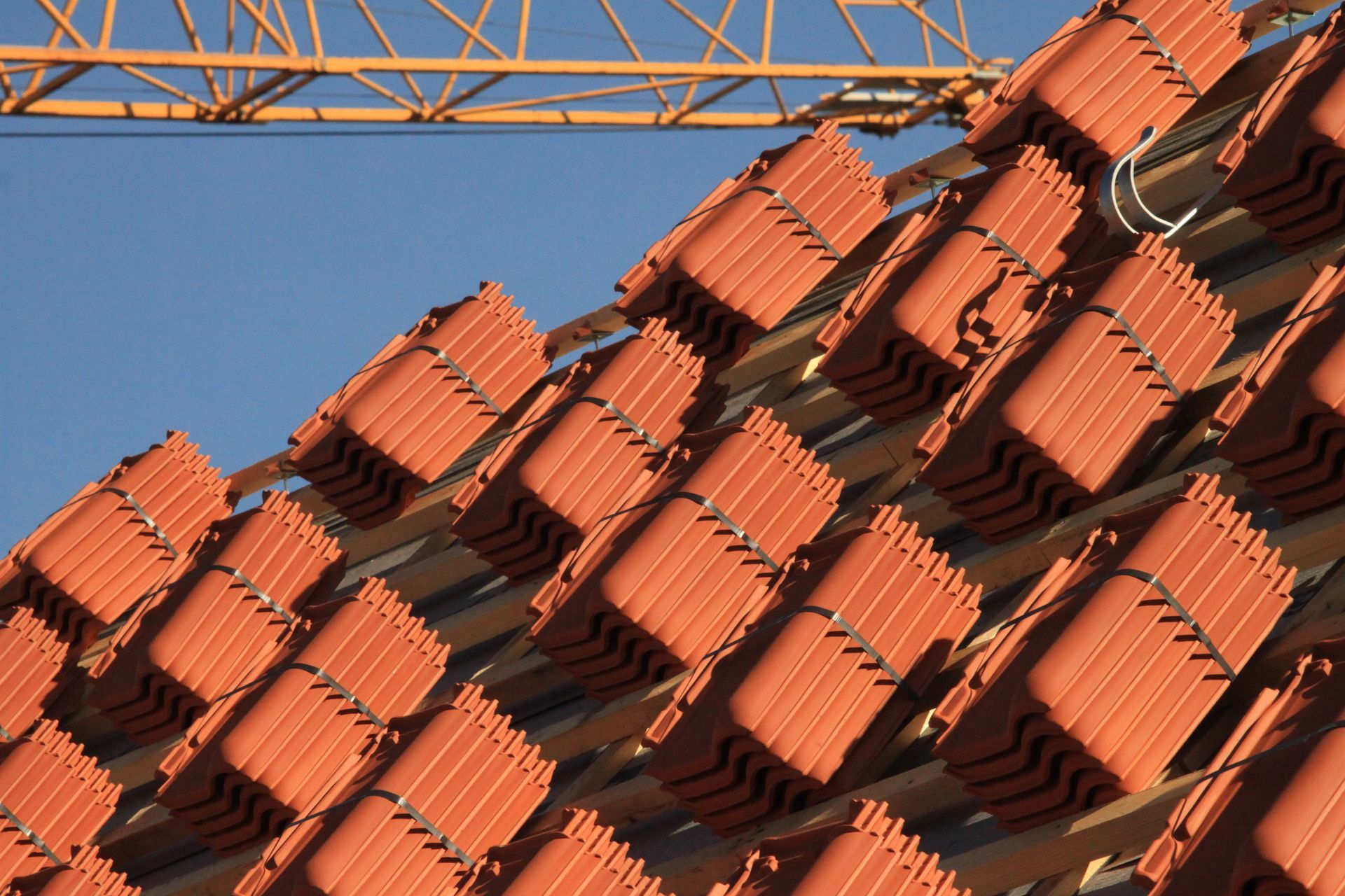 Piles de tuiles rouges sur un chantier, prêtes à être posées.