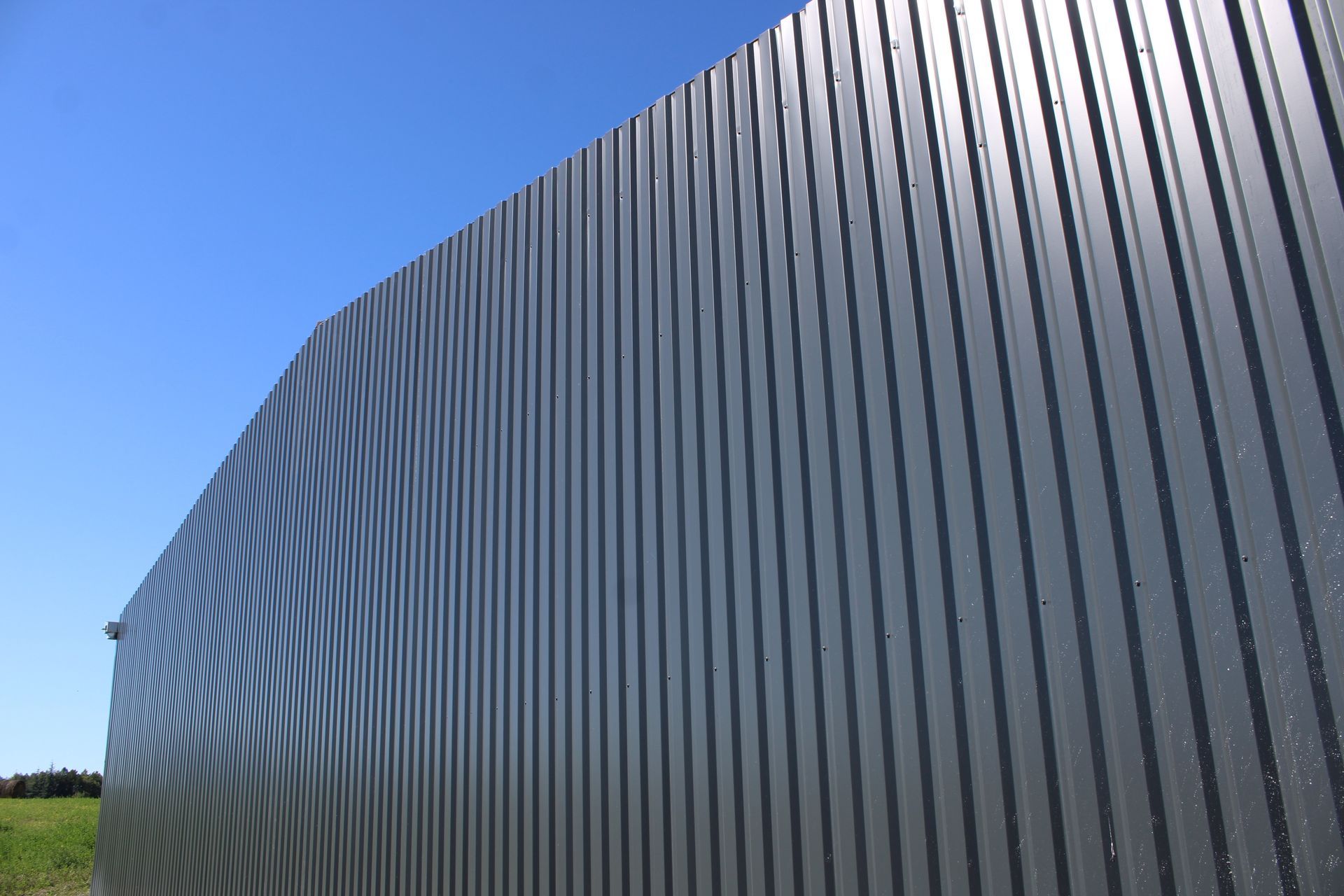 Façade d'un bâtiment en tôle ondulée se détachant sur un ciel bleu.